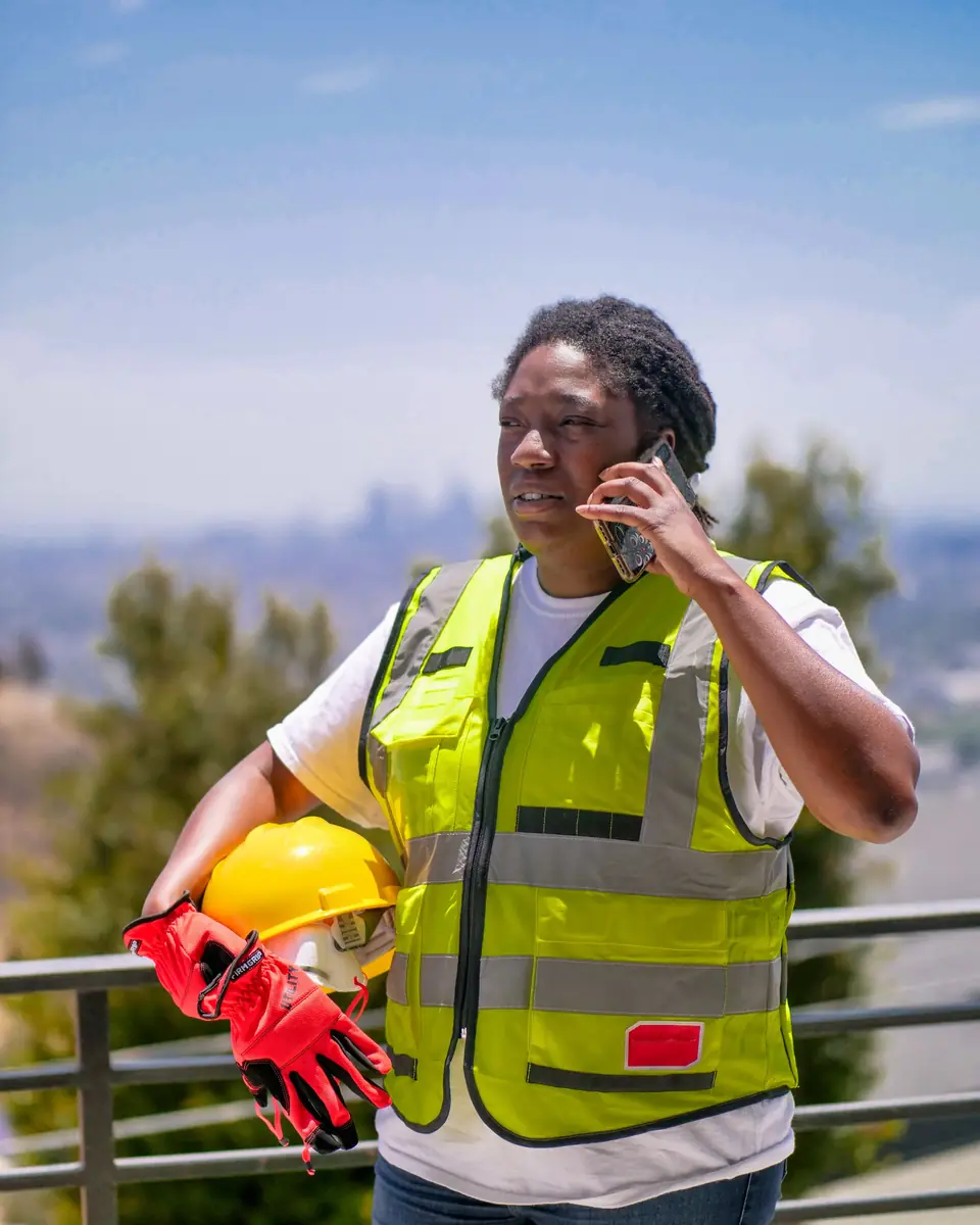 A contractor in a safety vest on a phone call at a job site
