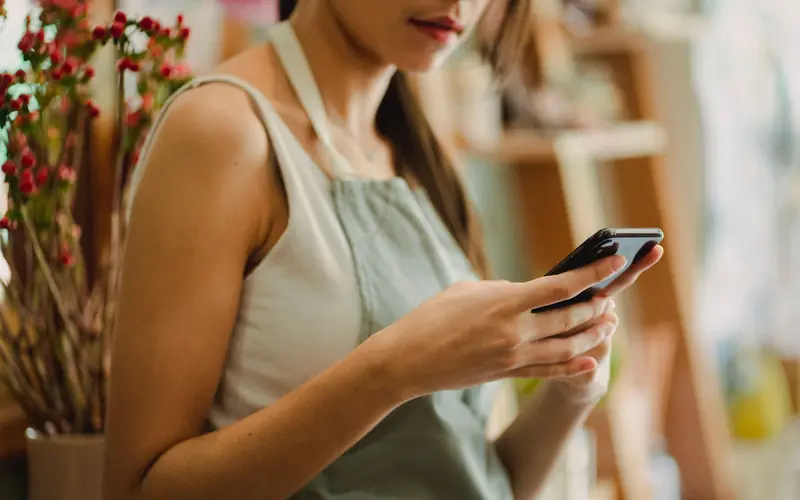 A shop owner checking her business on a smartphone